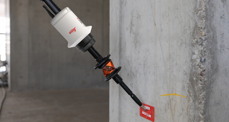 Leica AP20 AutoPole held at an angle to a concrete wall to mark the location for a drill hole.